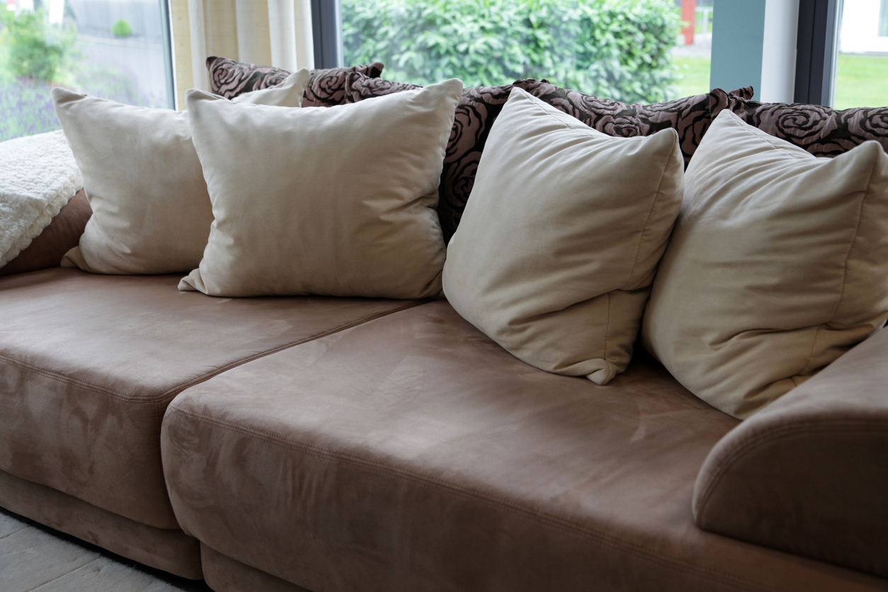 Brown upholstered sofa with beige pillows